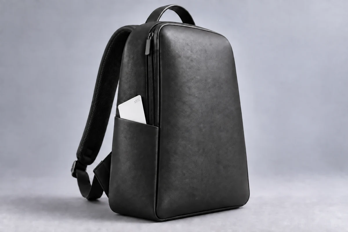 Sculptural charcoal leather backpack with white Still Card tucked into its side pocket