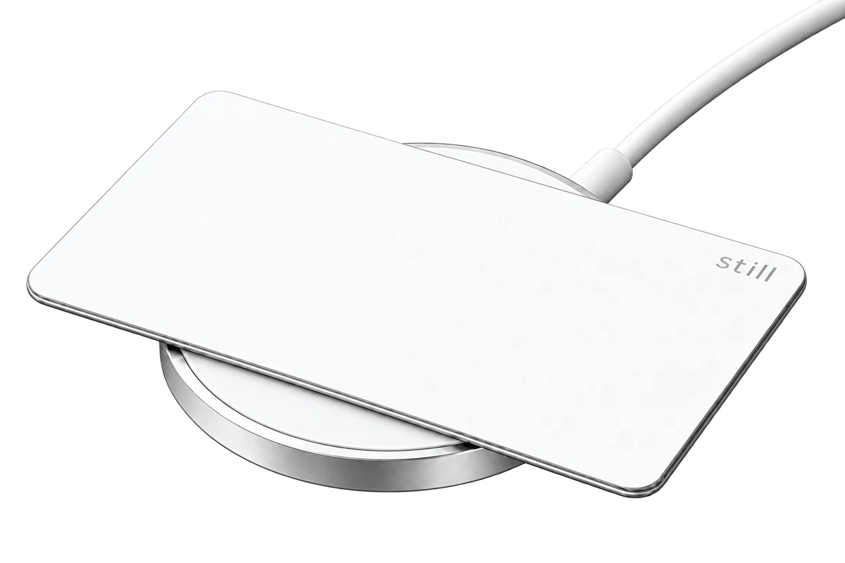 White Still Card resting on a round magnetic wireless charging puck, product rendering